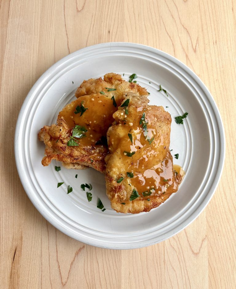 Honey Garlic Chicken cooked crispy on a plate with garnish.