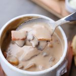 Creamy mushroom soup served in a bowl with a spoonful of soup.